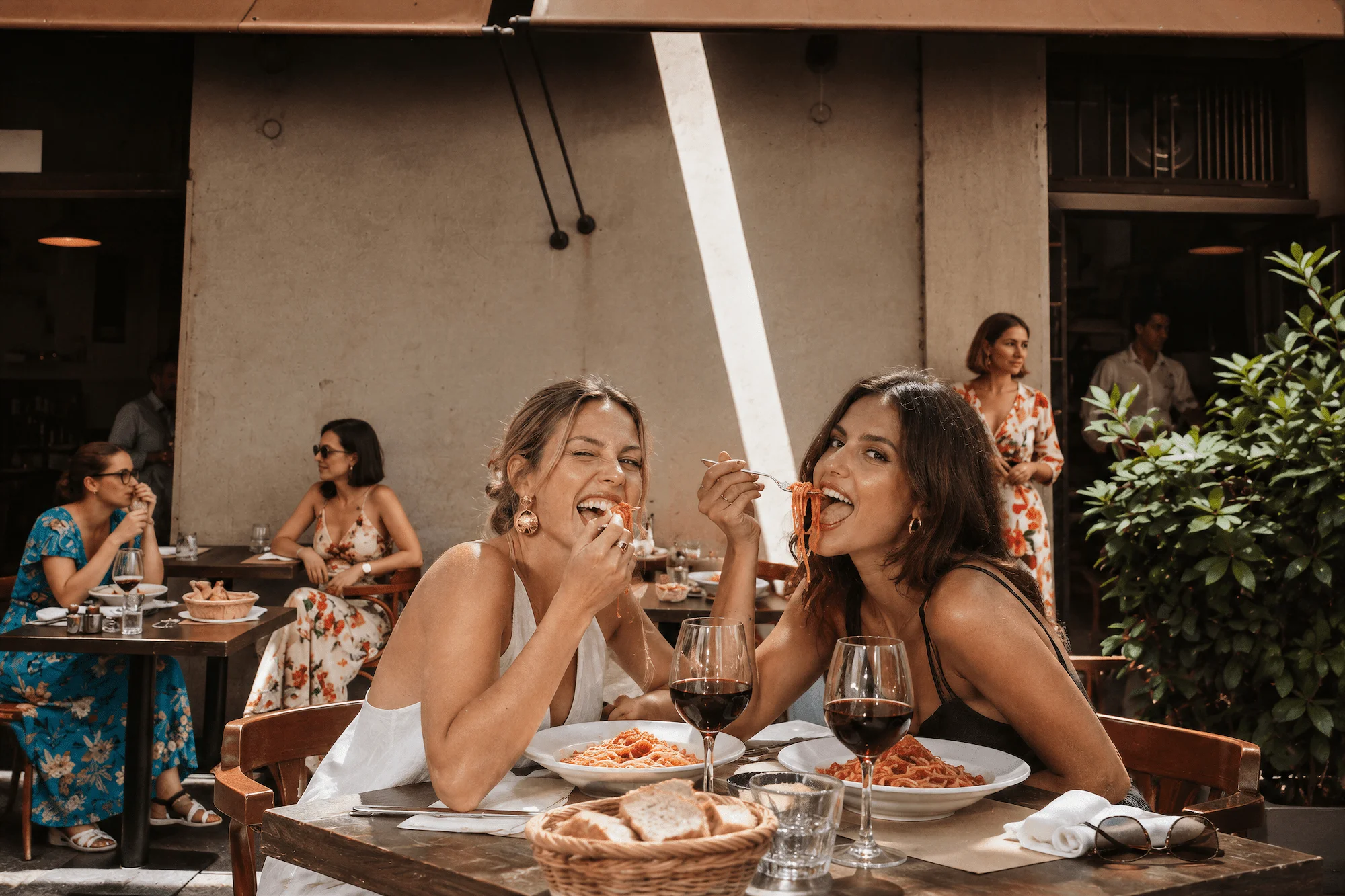 Two guests tasting pasta at an outdoor table